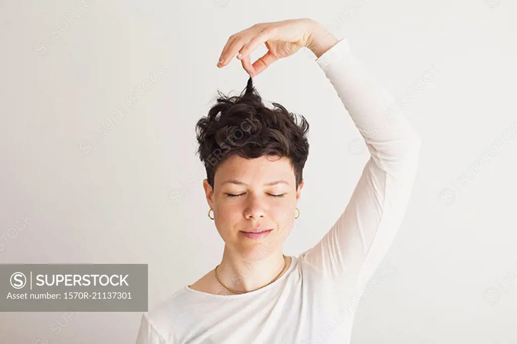 Close-up of happy mid adult woman holding her hair against white background