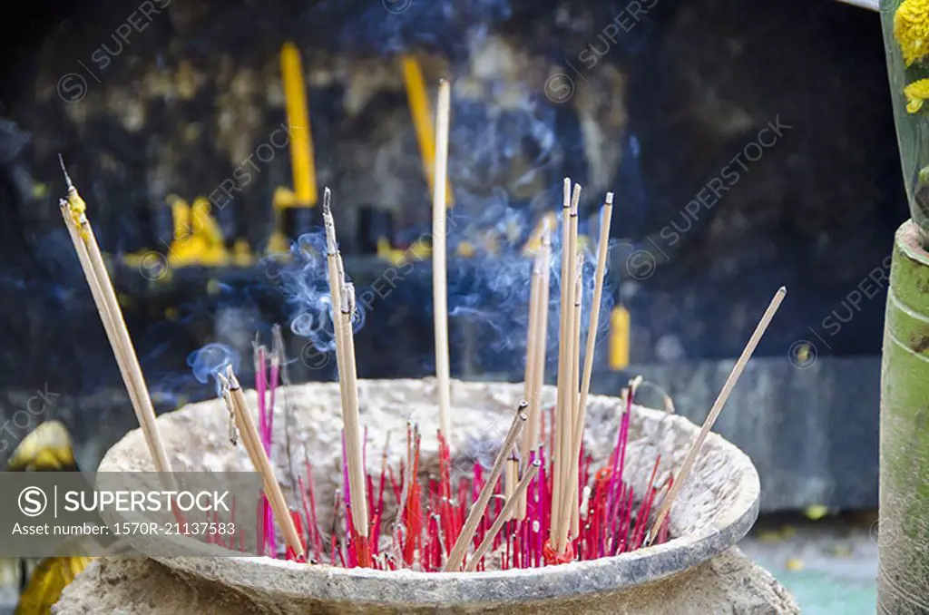 Smoke emitting from incense sticks in container at temple