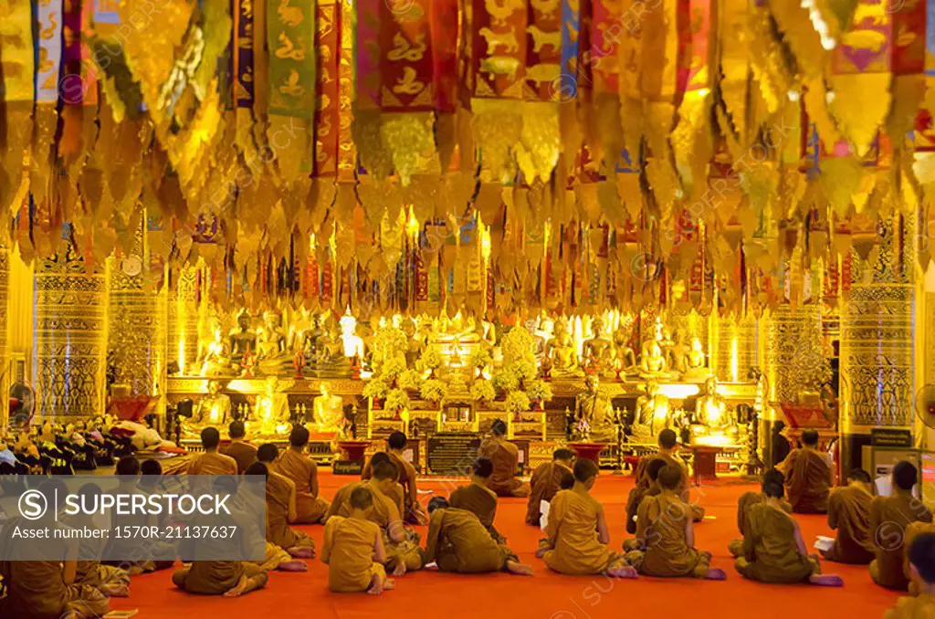 Rear view of monks sitting in Wat Chedi Luang temple