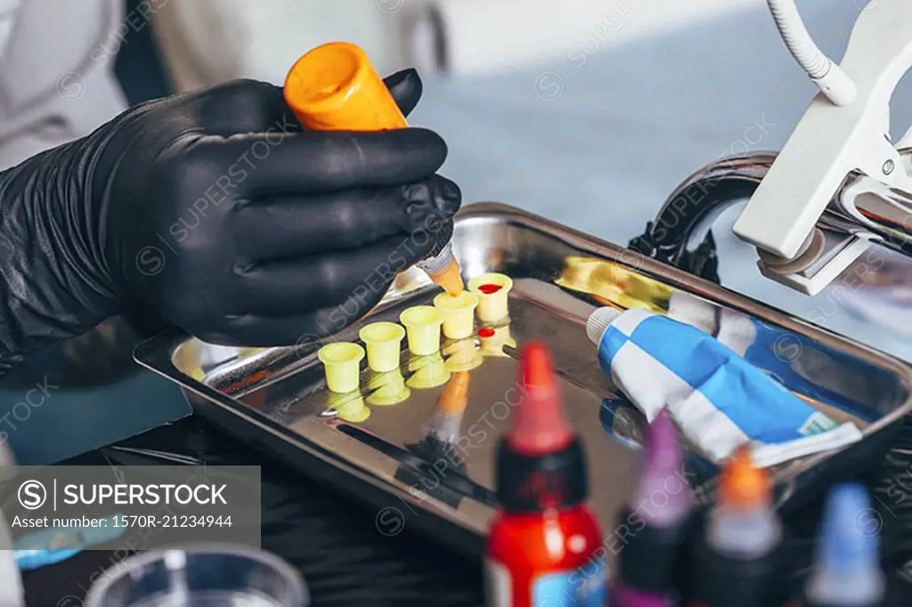 Cropped image of tattoo artist filling ink in containers at art studio