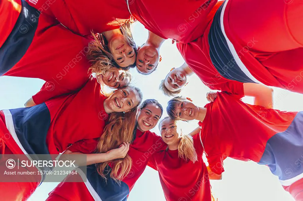 Directly below shot of soccer players huddling against clear sky
