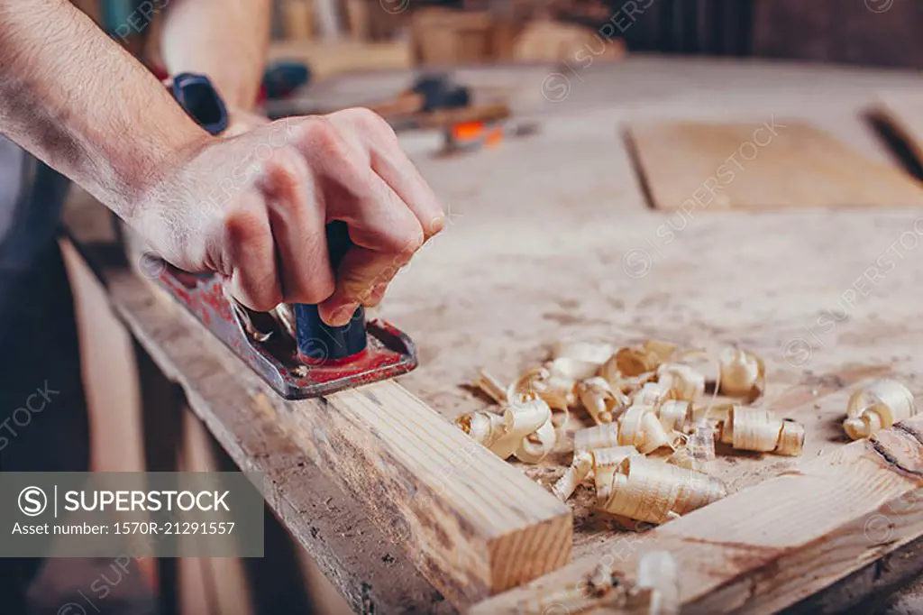 Midsection of carpenter planing wood at workshop