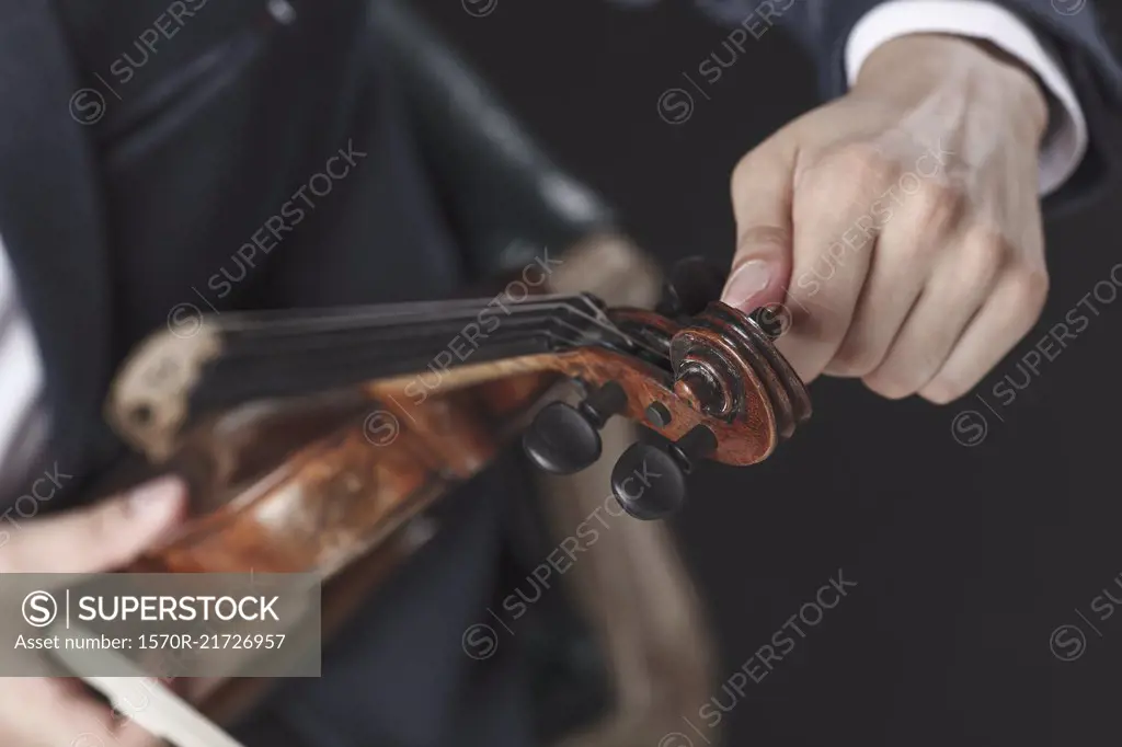 Cropped image of musician tuning violin strings