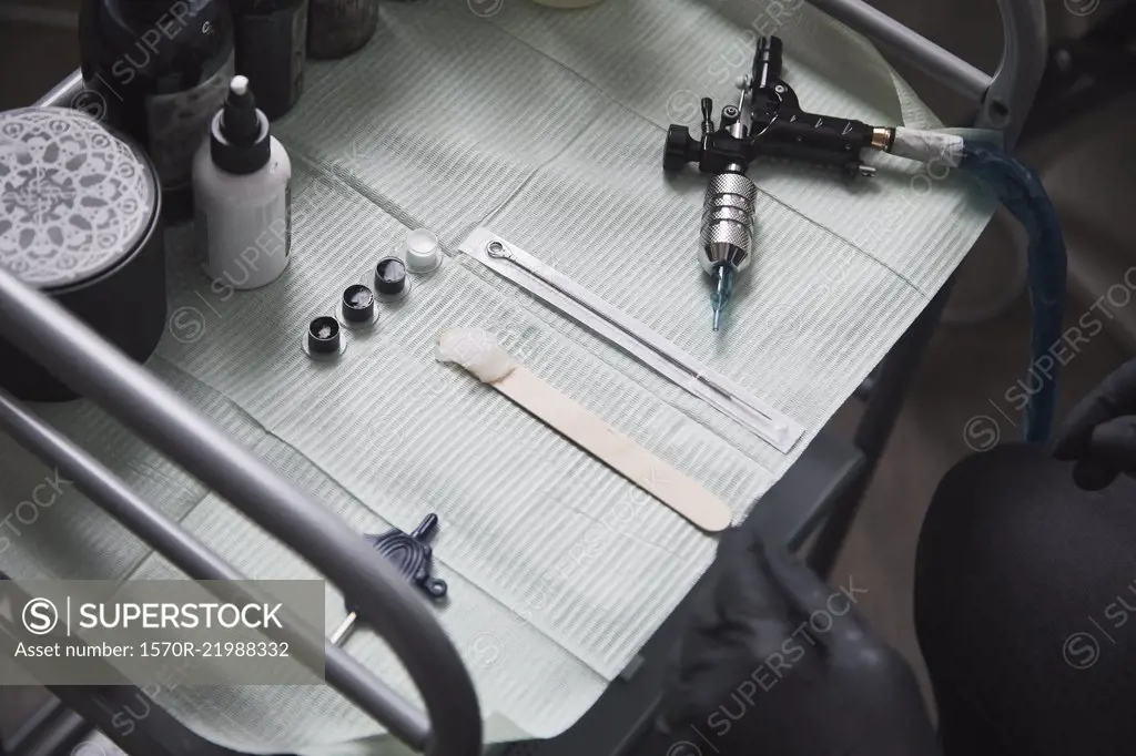 High angle view of tattoo artist sitting by tools on table