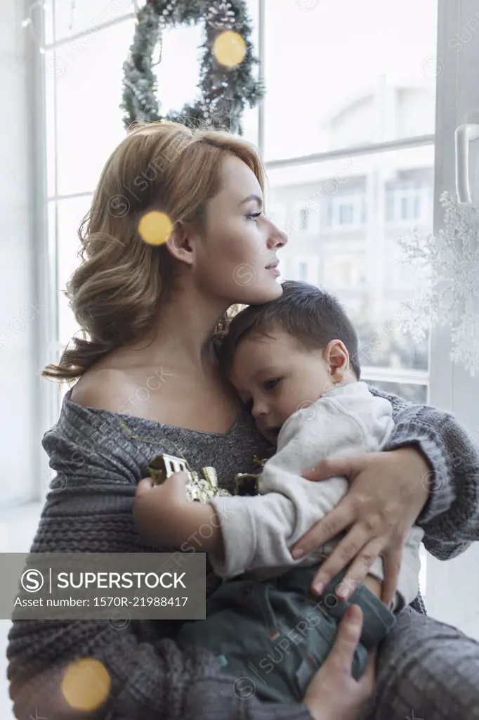 Young woman sitting with son by window at home