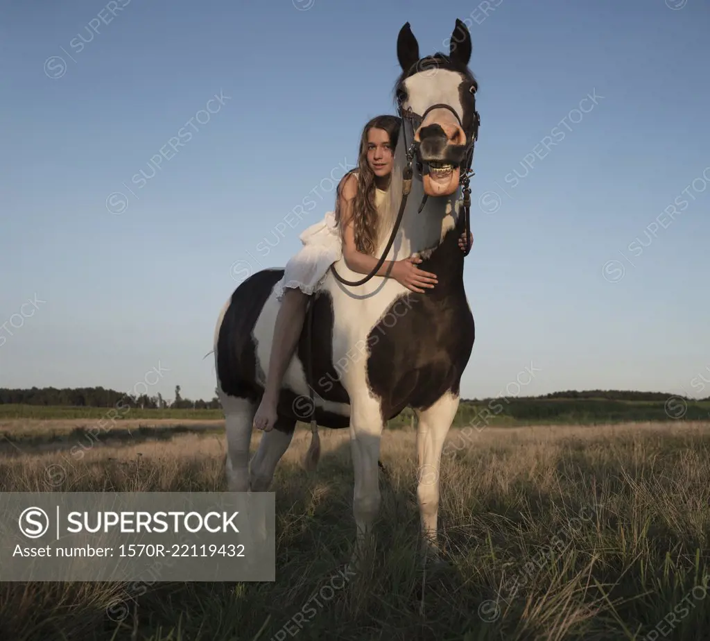 Portrait girl laying on horse in rural field