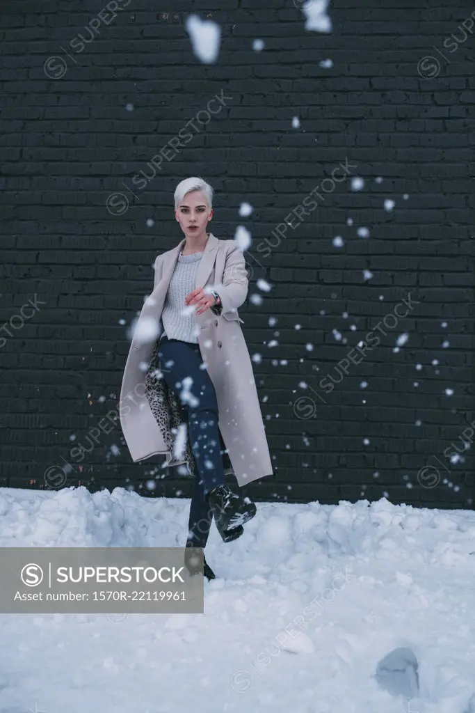 Portrait young woman kicking snow