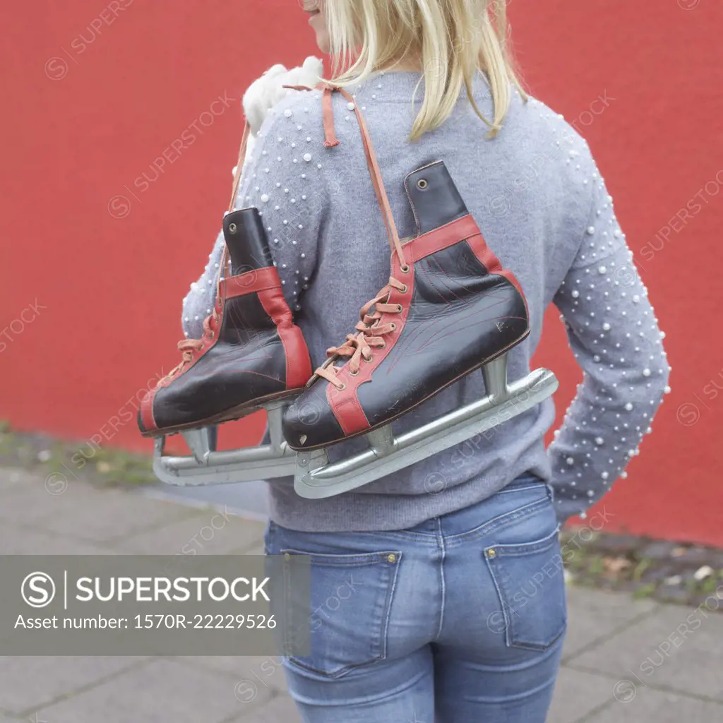 Woman carrying ice skates over shoulder