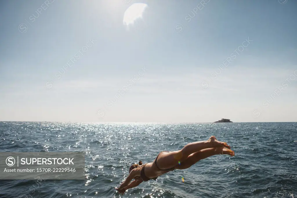 Woman diving into sunny blue ocean, Rovinj, Croatia