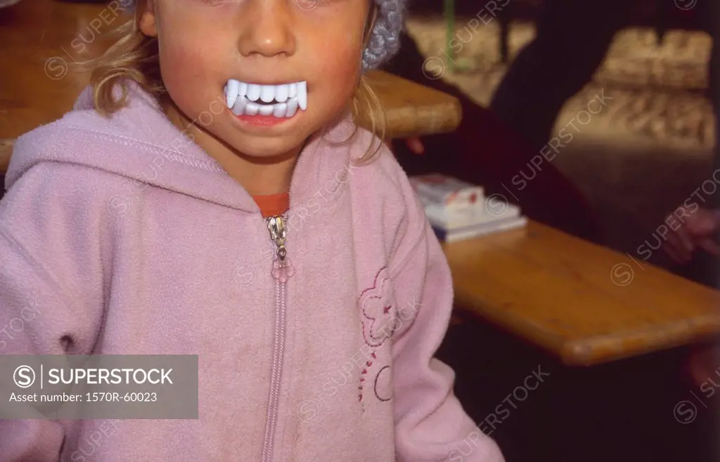 A child wearing fake vampire teeth