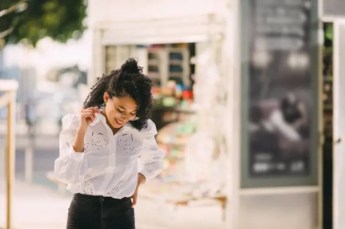 Happy young woman walking on urban sidewalk