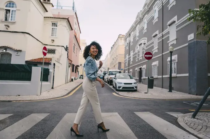 Portrait happy, stylish woman crossing city street