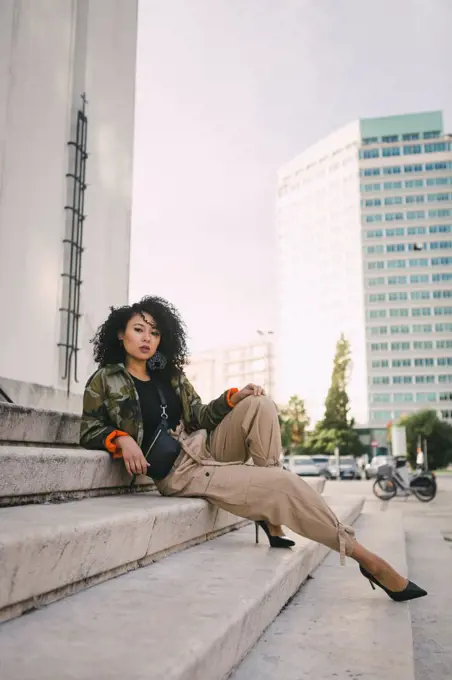 Portrait confident, stylish woman on urban steps