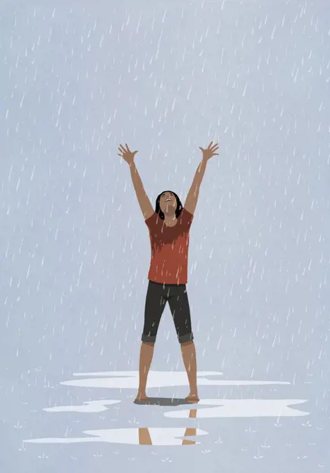 Barefoot, exhilarated woman with arms raised in rain