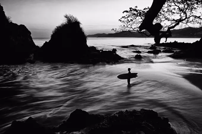 Silhouette boy with surfboard on ocean beach, Sayulita, Nayarit, Mexico