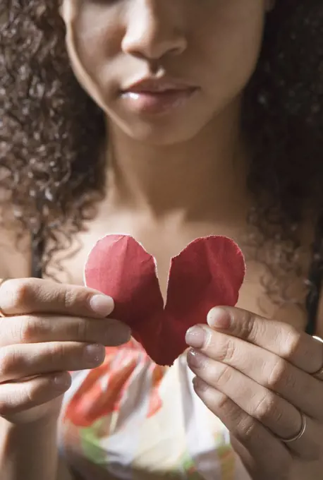 Young woman holding broken heart