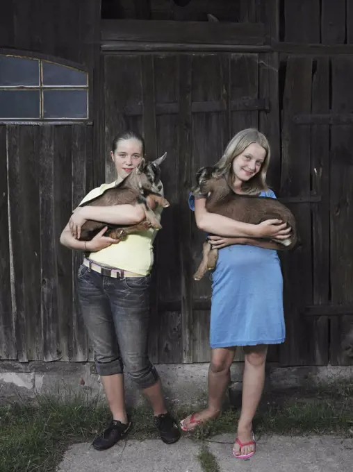 Two girls holding kid goats