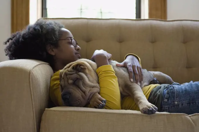 A young woman and her Shar-Pei napping on a couch