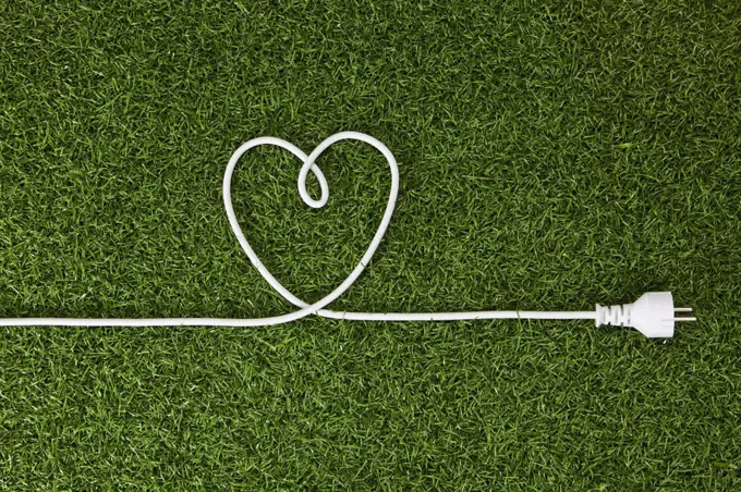 An electrical cord arranged in a heart shape on grass