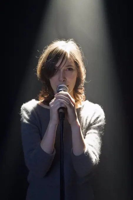 A Woman Standing Behind A Microphone