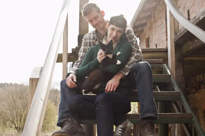 A couple holding and petting a cat