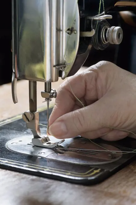 A woman threading a needle on a sewing machine, detail of hand