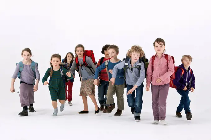 A group of school kids wearing backpacks and running forward