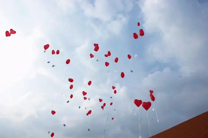 Many red heart shaped helium balloons floating up