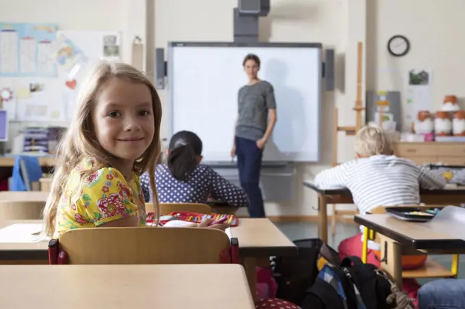 Girl sitting in classroom, smiling