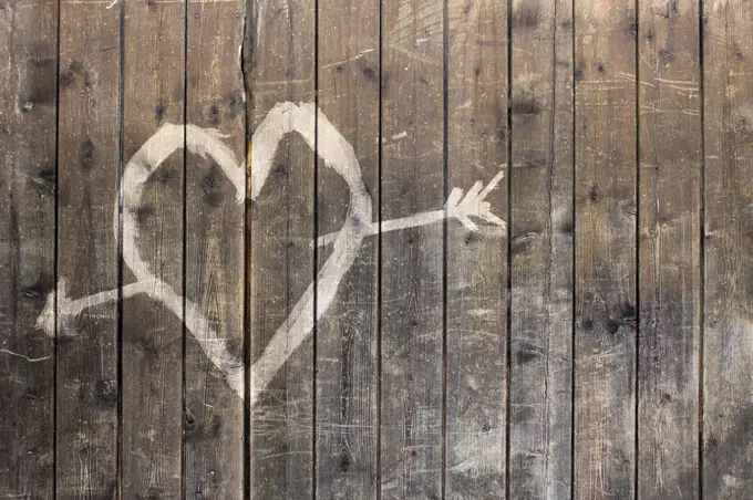 Heart shape with arrow symbol on wooden fence