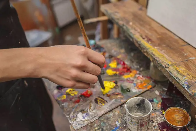 High angle view of artist mixing paint in palette at studio