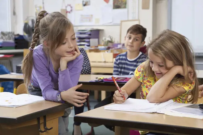 Students writing on book in classroom