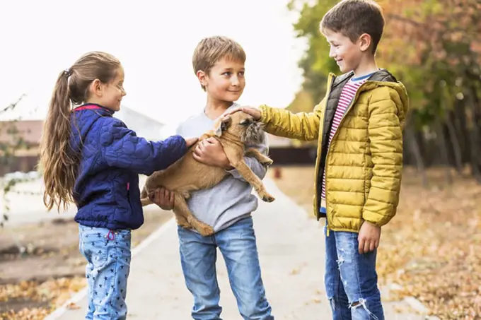 Children playing with dog outdoors