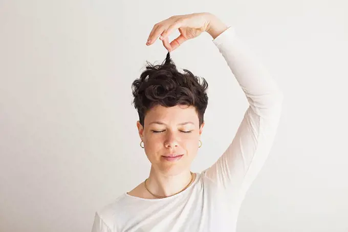 Close-up of happy mid adult woman holding her hair against white background