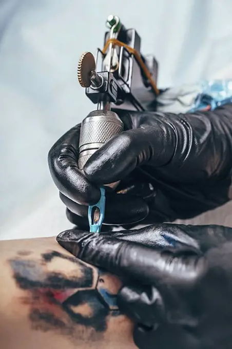 Artist tattooing design on human hand