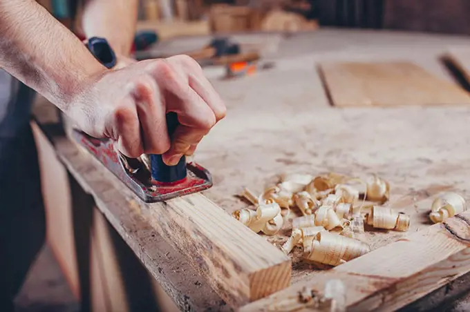 Midsection of carpenter planing wood at workshop