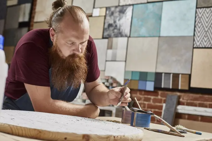 Man holding sand paper while leaning on workbench