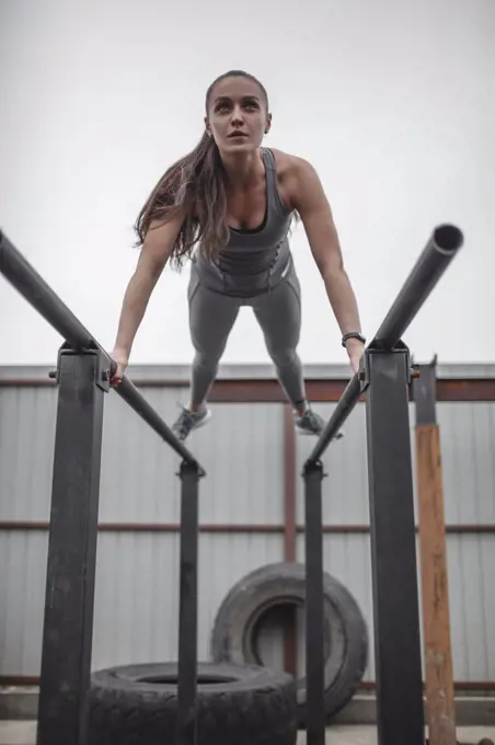 Low angle view of female athlete doing push-ups on parallel bars during crossfit training