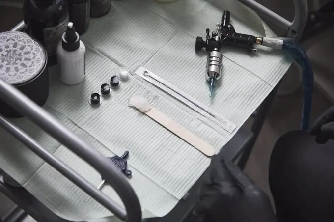 High angle view of tattoo artist sitting by tools on table