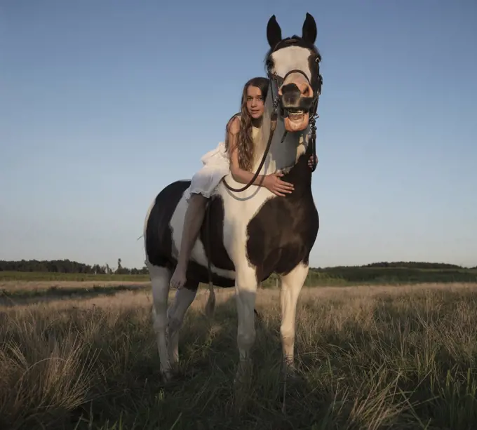 Portrait girl laying on horse in rural field