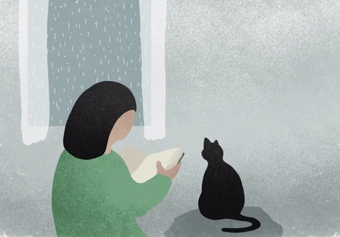 Woman with cat reading book next to rainy window