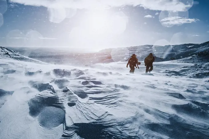 Father and son walking along sunny, snow covered mountain, Reykjadalur, Iceland