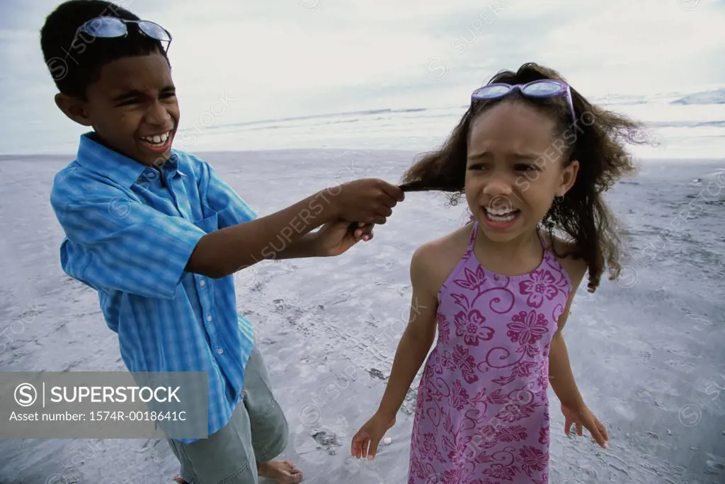 Boy pulling a girl's hair on the beach