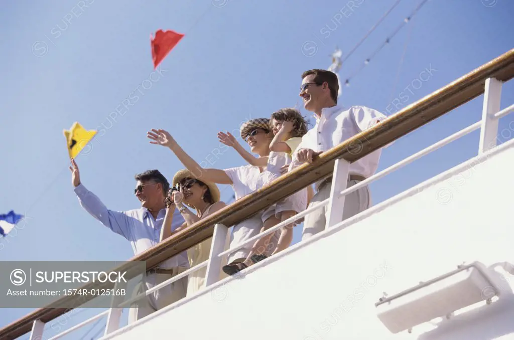 Low angle view of five people waving their hands on the deck of a cruise ship