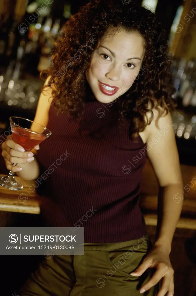 Portrait of a young woman holding a martini at a bar