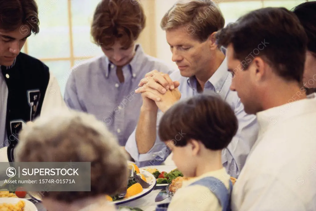 Members of a family praying at the dinner table