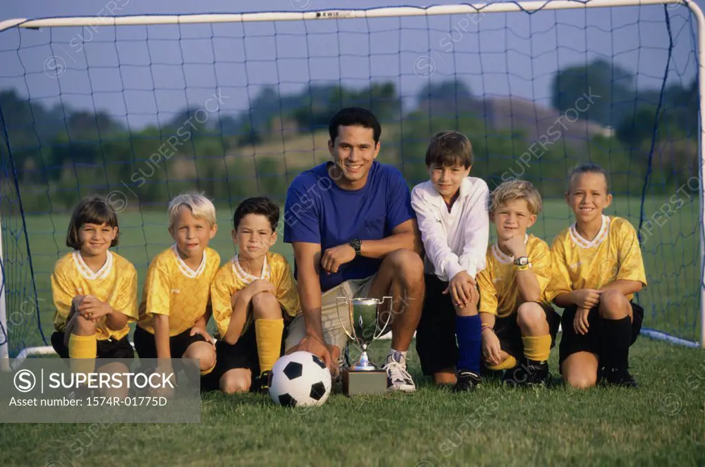 Portrait of a soccer team and coach on a field with a trophy