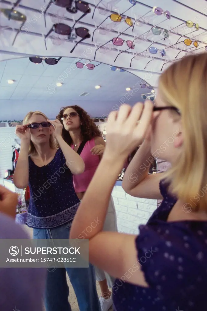 Three young women shopping for sunglasses