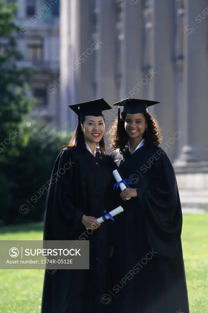 Two female graduates holding diplomas