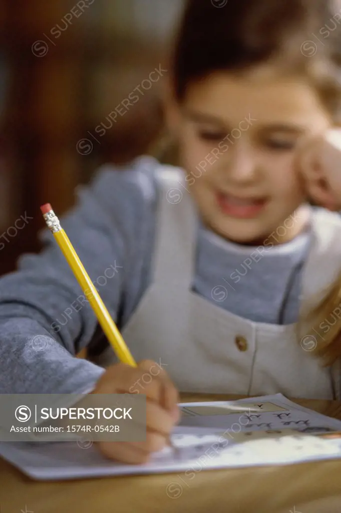 Girl writing on paper with a pencil